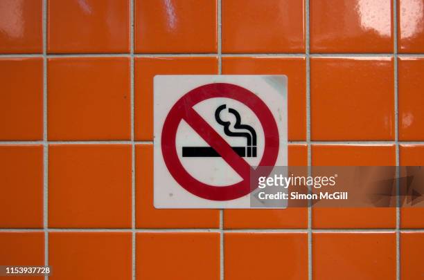 'no smoking' sign on a wall with glossy orange tiles - no smoking sign stock pictures, royalty-free photos & images