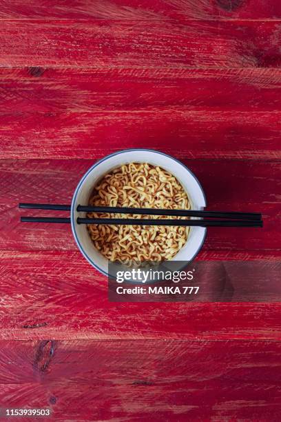 instant noodles served in bowl with chopsticks, against red rustic wood background - korean chopsticks stock pictures, royalty-free photos & images