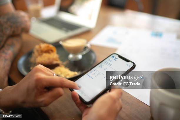 woman checking account statement of her digital investment on her mobile phone - bank statement stock pictures, royalty-free photos & images