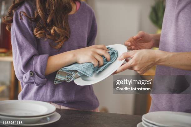 meisje helpen moeder schoonmaken van gerechten in de keuken - drying stockfoto's en -beelden
