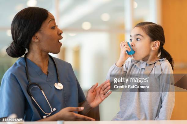 el médico femenino asiste al paciente asmático joven - asmático fotografías e imágenes de stock