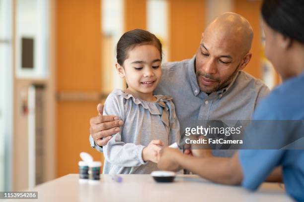 father holding young daughter at a doctors appointment - insulin pen stock pictures, royalty-free photos & images
