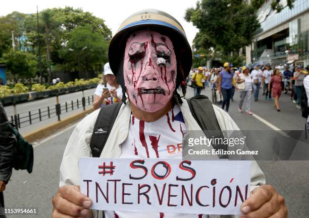 Venezuelan wearing a mask holds a sign that reads 'SOS intervention' as people gather at PNUD for a demonstration called by opposition leader Juan...