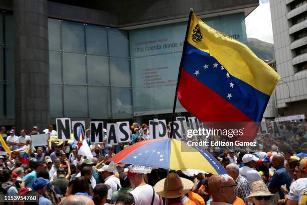 Venezuelans wave flags and hold signs as people gather at PNUD for a demonstration called by opposition leader Juan Guaidó during the 208th...