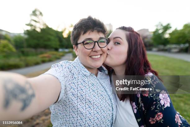 twee vrouwen omhelzen en het nemen van een selfie op een avondwandeling - fat lesbian stockfoto's en -beelden