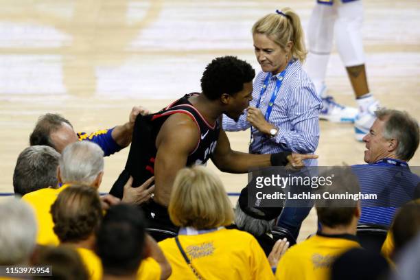 Kyle Lowry of the Toronto Raptors argues with Warriors minority investor Mark Stevens after Lowry chased down a loose ball in the second half against...
