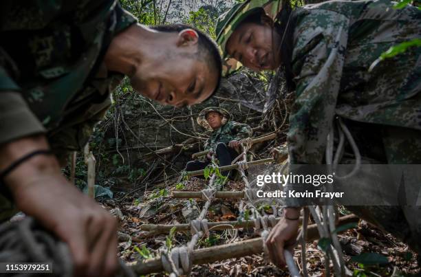 Chinese ethnic Lisu honey hunters Dong Haifa,left, and Mi Qiaoyun, center, and Ma Yongde build a makeshift rope ladder as they prepare to gather wild...