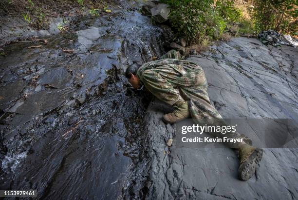 Chinese ethnic Lisu honey hunters Ma Yongde takes a drink from a stream after gathering wild cliff honey from hives in a gorge on May 31, 2019 near...