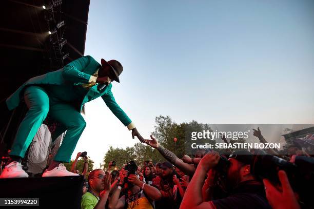 Ivorian singer Alpha Blondy greets fans as he performs on stage during the 31st Eurockeennes rock music festival in Belfort, eastern France, on July...