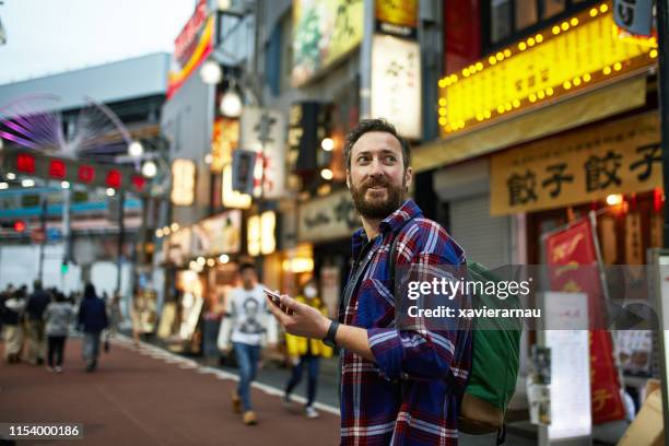 caucasian male tourist navigating tokyo with smart phone - japan tourism stock pictures, royalty-free photos & images