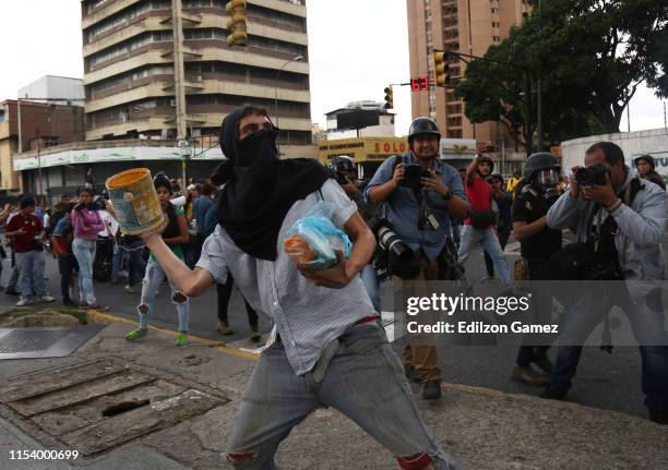 Protestors throw stones and other objects to the Venezuelan National Police during a demonstration called by opposition leader Juan Guaidó as part of...