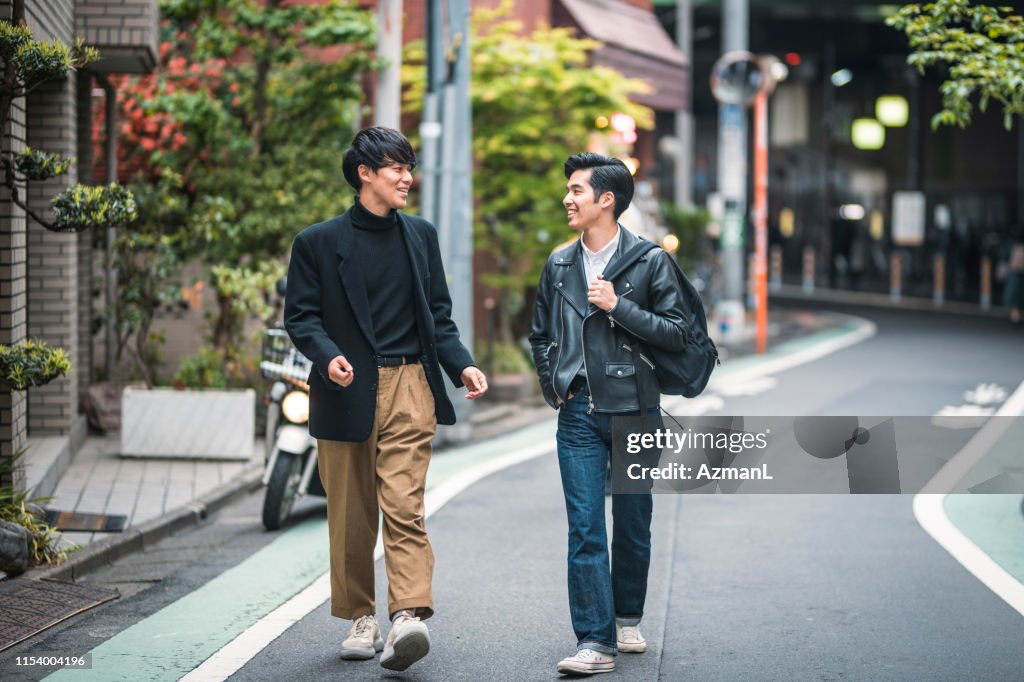 Amigos masculinos japoneses relajados caminando y hablando en Tokio