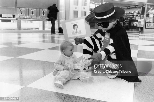 The McDonald's Hamburglar hands a children's Happy Meal to 1-year-old Cameron Rose Conlon in the United Airlines terminal at O'Hare International...