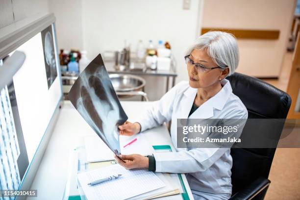 médico femenino japonés senior estudiando imágenes de rayos x - beautiful woman chest fotografías e imágenes de stock