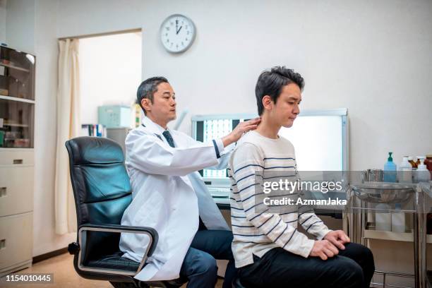 male japanese doctor examining a patient - sala de exame médico imagens e fotografias de stock