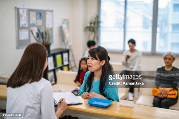 japanese nurse assisting patients in hospital waiting room - waiting room clinic stock pictures, royalty-free photos & images