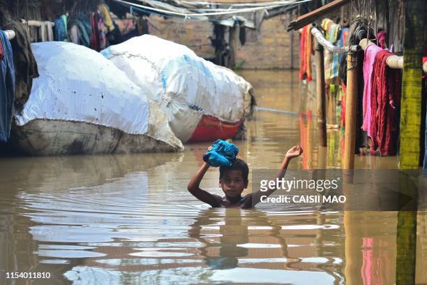 An Indian boy wades through a flooded area at Ragailong colony following monsoon rains in Dimapur, in the northeastern Indian state of Nagaland on...