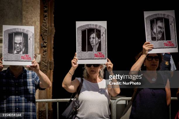 People hold banners showing the faces of imprisoned Catalan separatist leaders Jordi Turull, Carme Forcadell and Jordi Cuixart in Barcelona,...