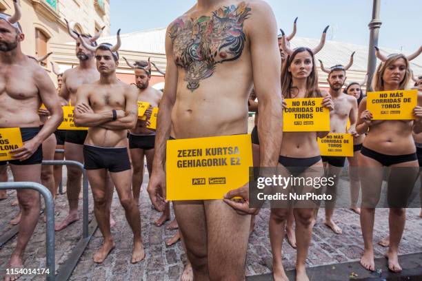 Nude activists against animal cruelty hold banners anti bullfightings during a protesting performance before the San Fermin celebrations in the main...