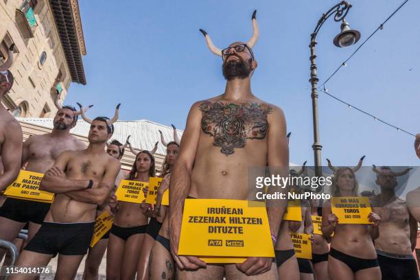 Activists against animal cruelty hold banners anti bullfightings in many languages and horns in head during a protesting performance before the San...