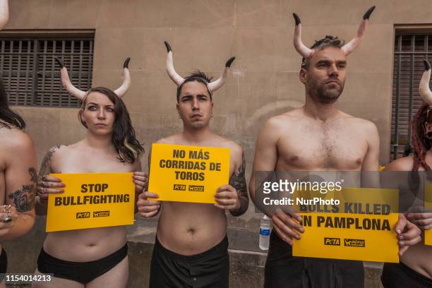Activists against animal cruelty hold banners anti bullfightings killings and horns in head in a protesting performance before the San Fermin...