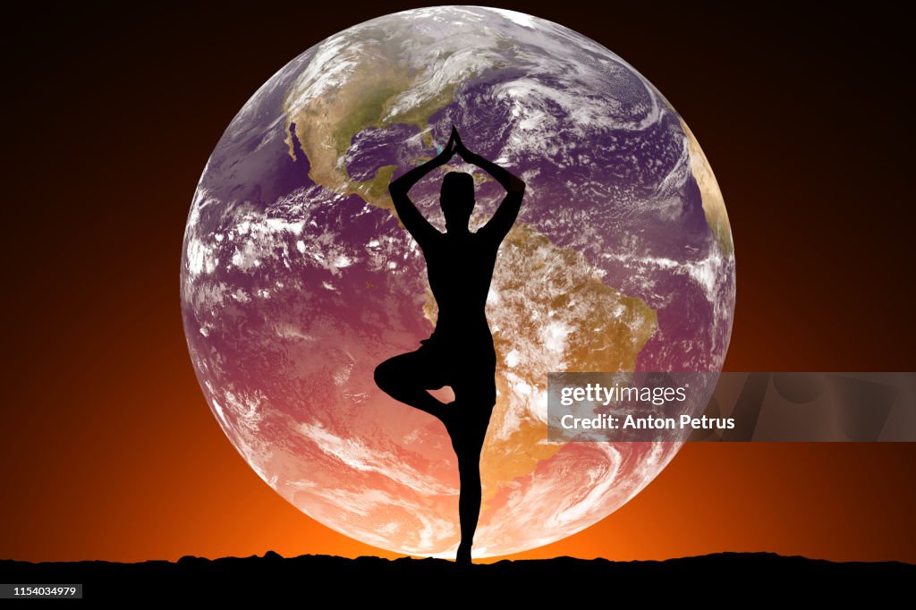 Silhouette of women doing yoga on the background of the planet Earth.