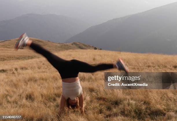 female hiker does cartwheel on grassy hillside - cartwheel stock pictures, royalty-free photos & images