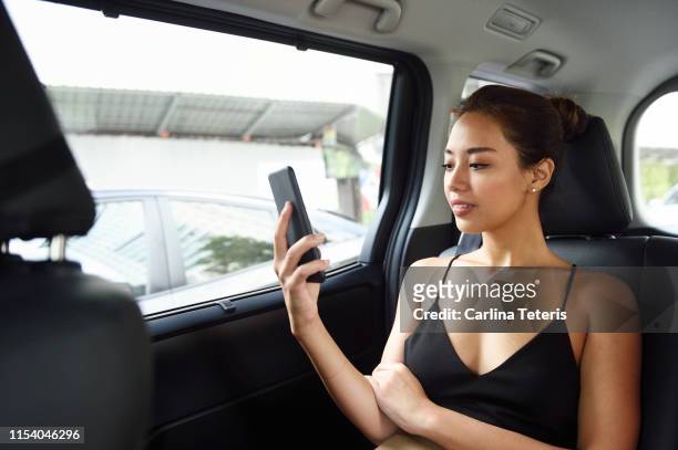 wealthy asian woman using her mobile phone in a car - beautiful filipino women stock pictures, royalty-free photos & images