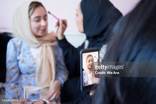 Young muslim women giving friend a make-over in bedroom