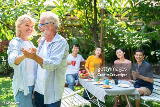 love lives forever! senior couple at home. handsome old man and attractive old woman are enjoying spending time together. having fun and dancing with family background. - tango stock-fotos und bilder