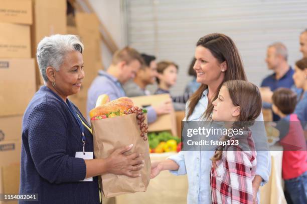 multi-ethnic group of volunteers work at food bank. - food insecurity stock pictures, royalty-free photos & images