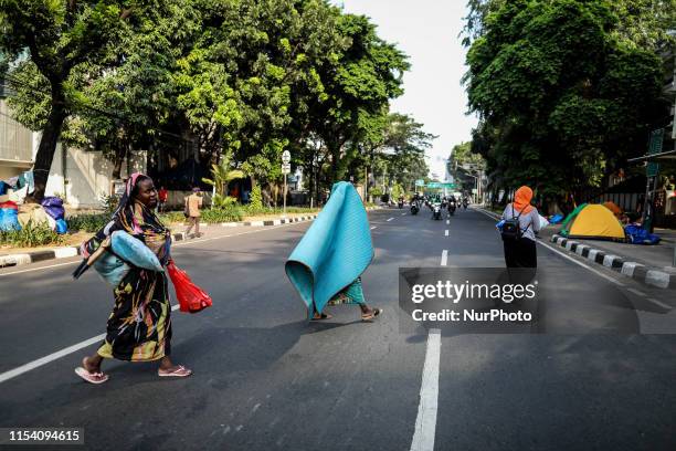 Sudanese migrant womans walk through next to a tent near Jakarta's UNHCR headquarters to protest their resettlement delays in Jakarta, Indonesia, on...