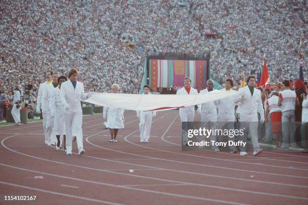 The Olympic flag is carried by former United States medalists led by Bruce Jenner, Wyomia Tyus, Parry O'Brien, Al Oerter, Billy Mills, John Naber,...