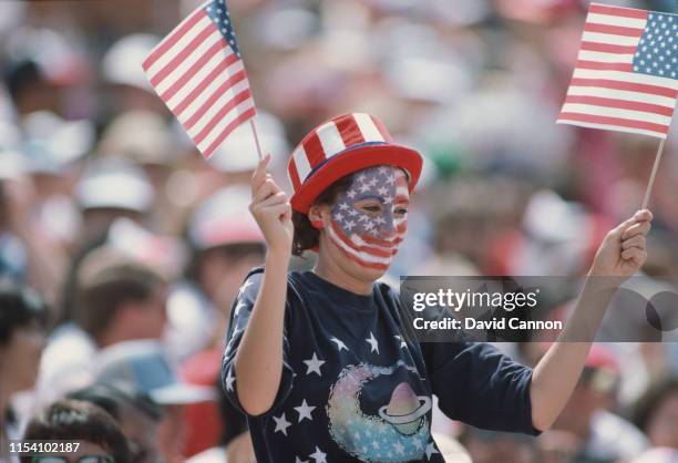 An American fan waves two United States flags during the opening ceremony for the XXIII Olympic Games on 28 July 1984 at the Los Angeles Memorial...