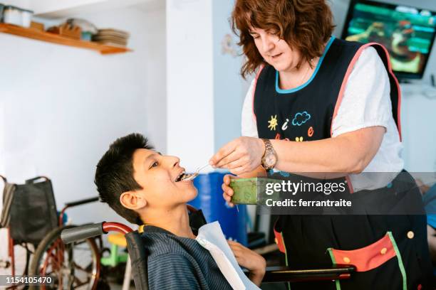 healthcare worker feeding kid with cerebral palsy - teenager cerebral palsy stock pictures, royalty-free photos & images