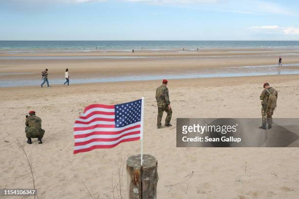 Soldiers of the Bundeswehr, the German armed forces, walk near an American flag presumably left by a visitor on Omaha Beach in Normandy on the 75th...