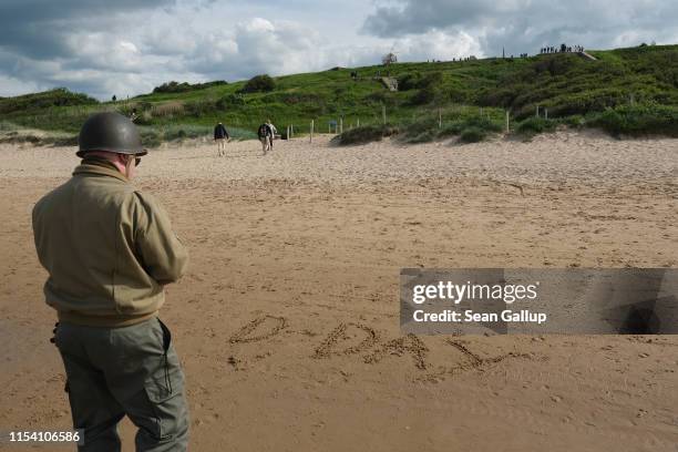 World War II re-enactor looks at "D-Day" scrawled in the sand on Omaha Beach in Normandy on the 75th anniversary of the World War II Allied D-Day...