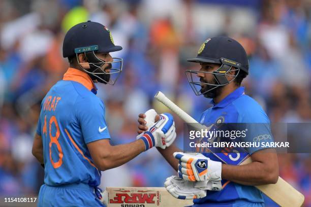 India's captain Virat Kohli congratulates India's Rohit Sharma as he passes him on his way back to the pavilion after losing his wicket for 103...