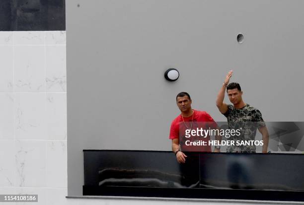 Portuguese forward Cristiano Ronaldo waves next to his brother Hugo Aveiro from the balcony of an apartment building in Funchal on July 6, 2019. -...