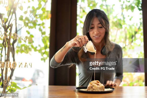 donna che versa condimento cremoso in un pane dolce - condensed milk foto e immagini stock