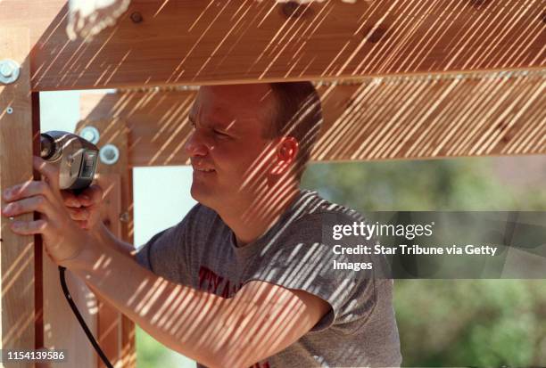 Minneapolis Mn, Wednesday 9/22/99----Vesa Loikas drills a section of a Sukkah as light from the bamboo roof filters across his face. Sukkahs are...