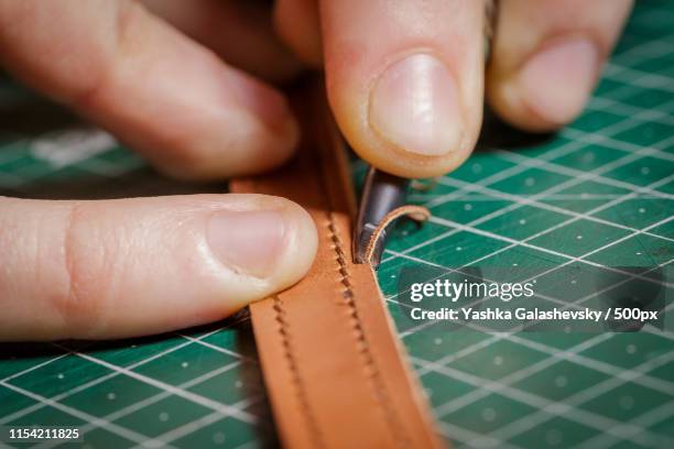 a person working as an artisan in his leather workshop removes the chamfer - maroquinerie photos et images de collection