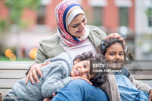 muslim family sitting on a bench - refugee health stock pictures, royalty-free photos & images