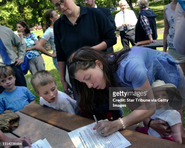 Shannon Nicoloff of St. Paul , right, holds daughter Olivia Nicoloff, nine months, as she signs a citizen's petition to repeal the new Conceal and...