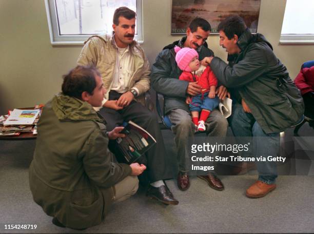 Jamal Amin admires Ahmad, the son of Hajar Gardi at the Fargo clinic where the three Kurdish Families went to get their immunizations and make...