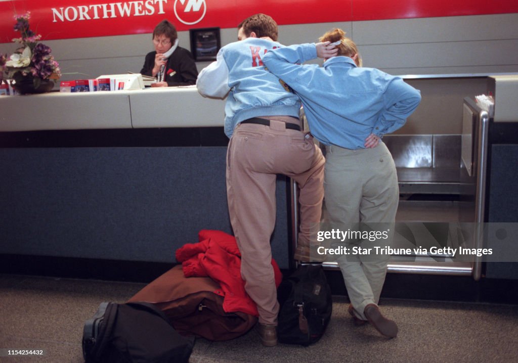 For NWA slowdown story - people at the Mpls airport affected by delayed or cancelled flights -- Trevor Groenjes, left, and wife Michaela Groenjes wait at the Northwest ticket counter at the Minneapolis airport Thursday as Northwest ticket agent Ann Hol