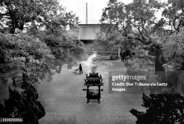 Lone monk, one of only 30 now dwelling at Beijing's Baiyunguan Si , sweeps leaves with a twig broom producing a repetive, soft, meditative sound in...