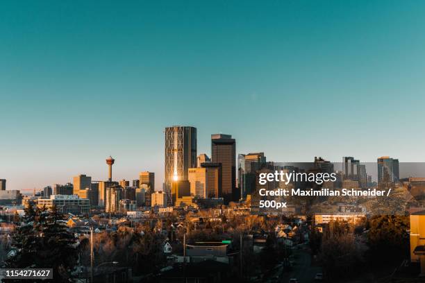 calgary skyline in the early morning with rays from rising sun reflecting off glass buildings - calgary bridge stock pictures, royalty-free photos & images