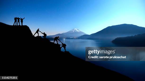 silhouette climbing group friends walking to hike up mountain .teamwork , helps ,success, winner and leadership concept . - community effort stock pictures, royalty-free photos & images