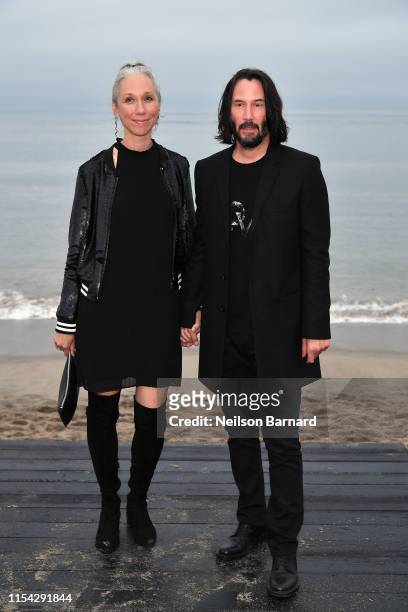 Alexandra Grant and Keanu Reeves attends the Saint Laurent Mens Spring Summer 20 Show on June 06, 2019 in Paradise Cove Malibu, California.